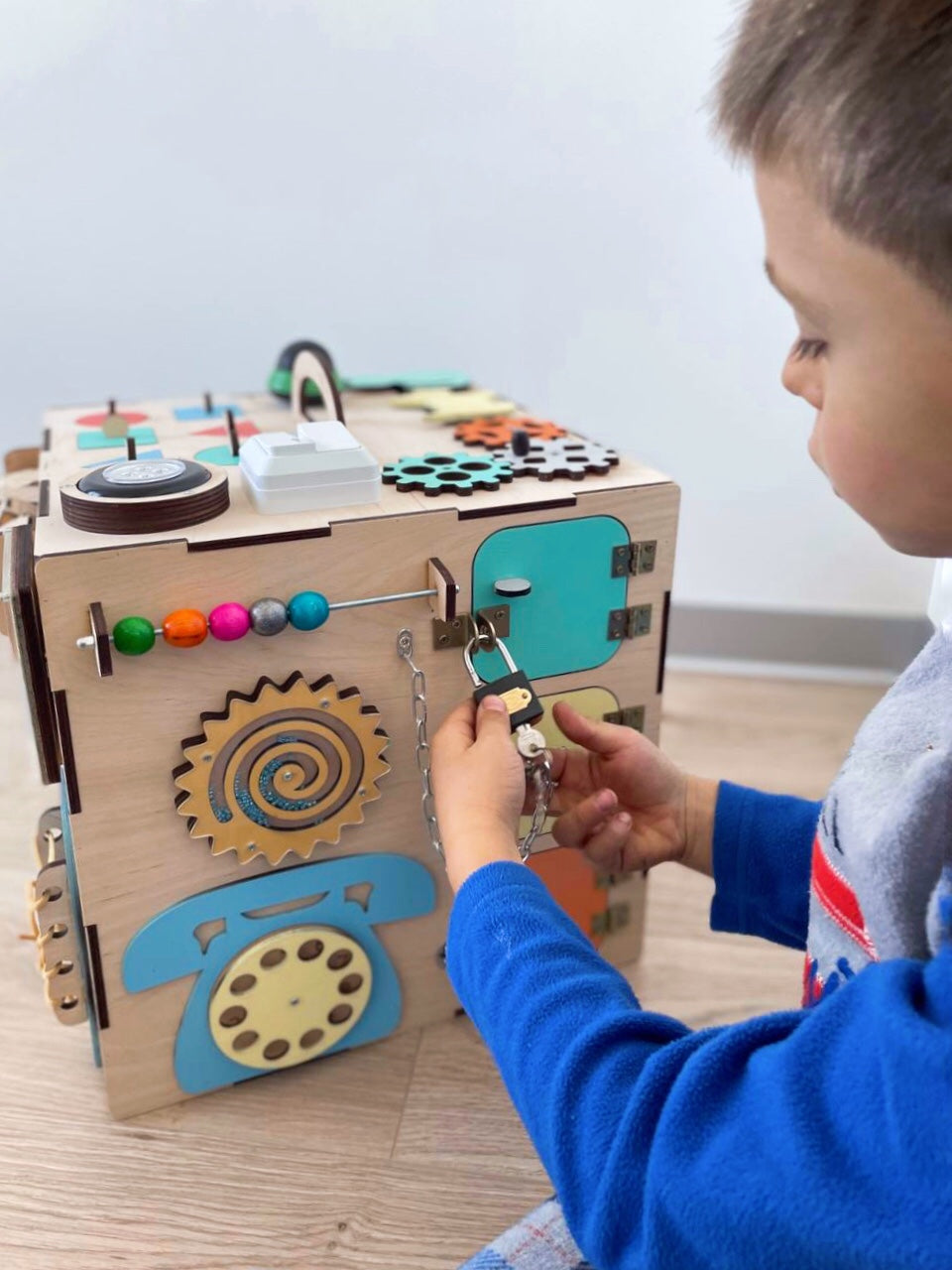 A colorful Busy Cube 13 inches featuring five busy boards with various engaging game elements for children's skill development.