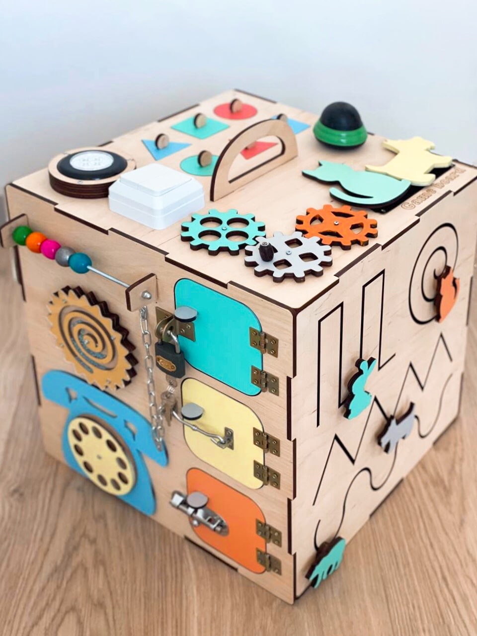 A colorful Busy Cube 13 inches featuring five busy boards with various engaging game elements for children's skill development.