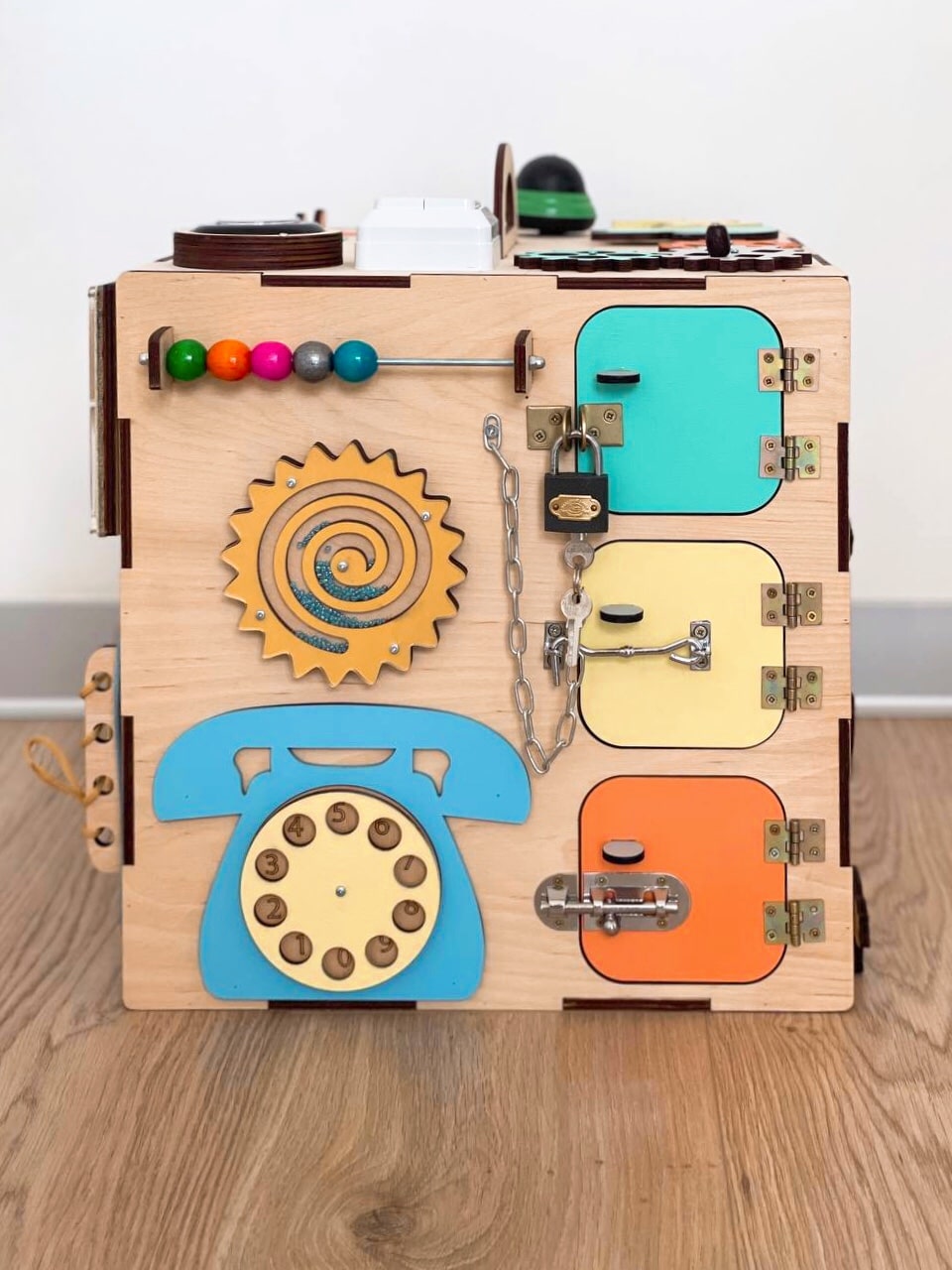 A colorful Busy Cube 13 inches featuring five busy boards with various engaging game elements for children's skill development.