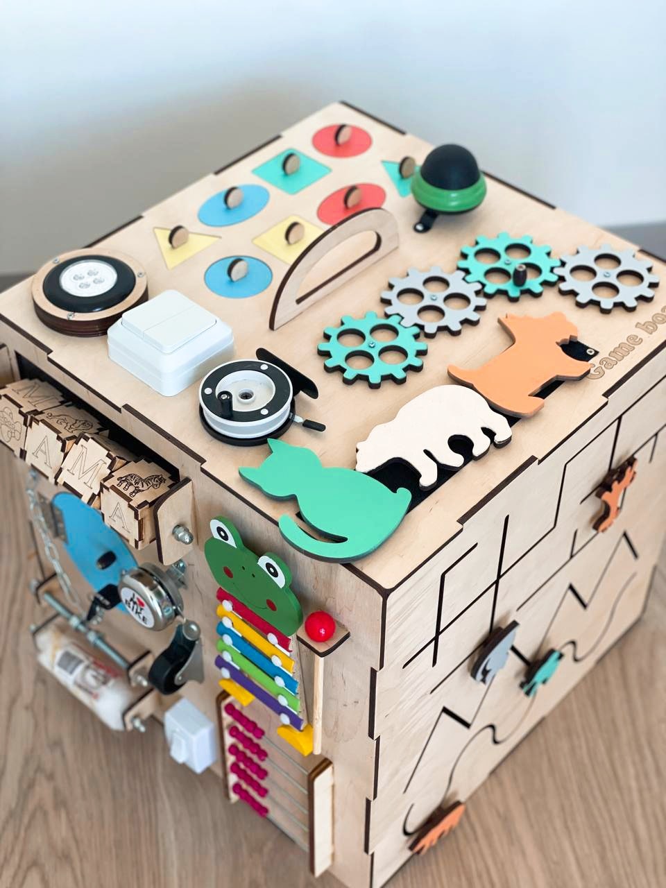 A colorful Busy Cube measuring 15 inches, featuring various engaging busy boards designed for children's skill development and creativity.