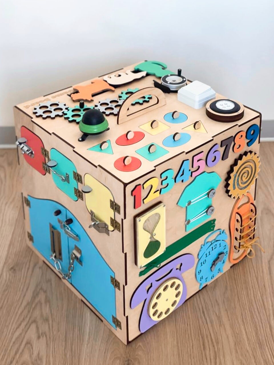 A colorful Busy Cube measuring 15 inches, featuring various engaging busy boards designed for children's skill development and creativity.