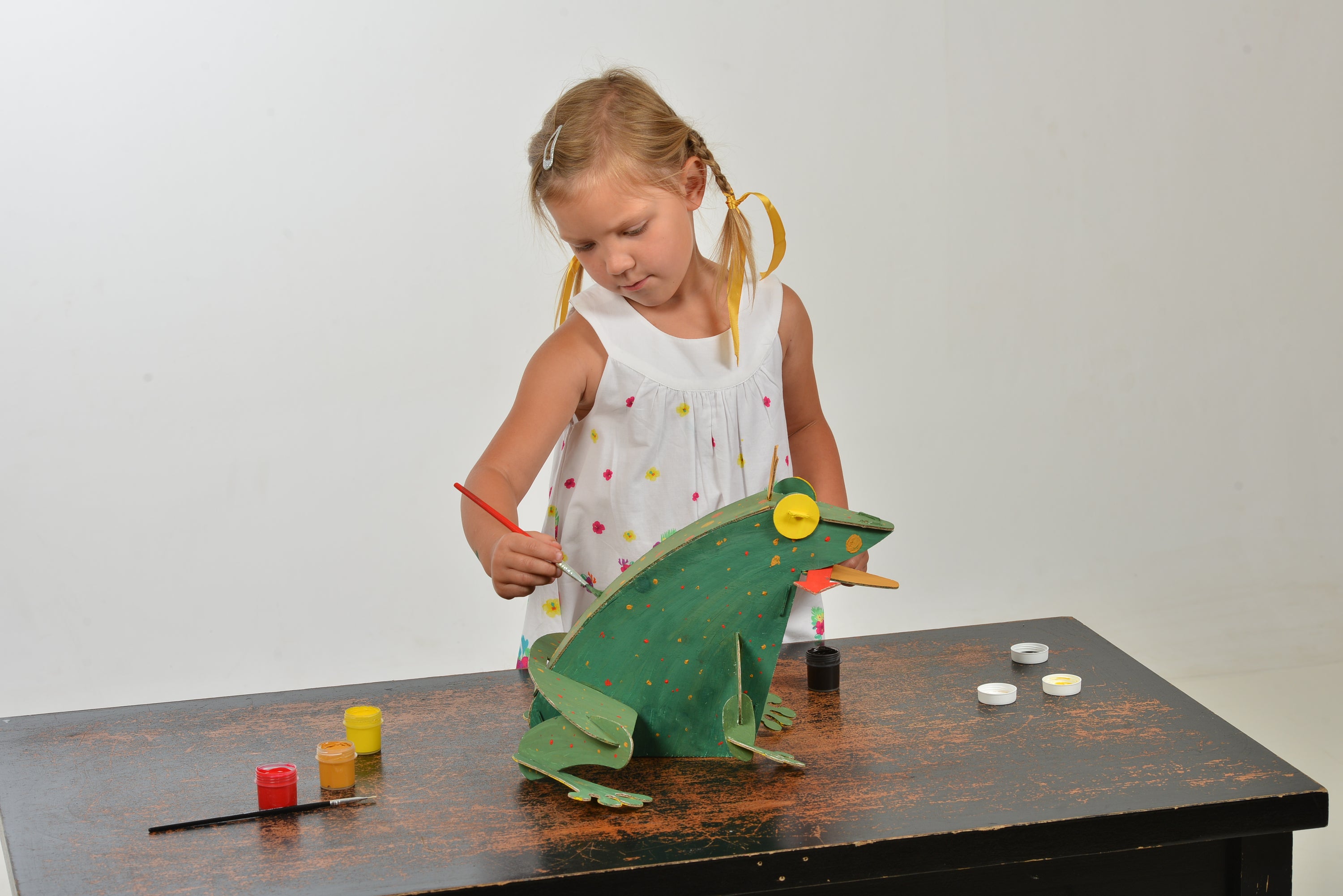 A colorful assembled cardboard frog model kit, showcasing its intricate parts and vibrant paint, perfect for children to build and decorate.