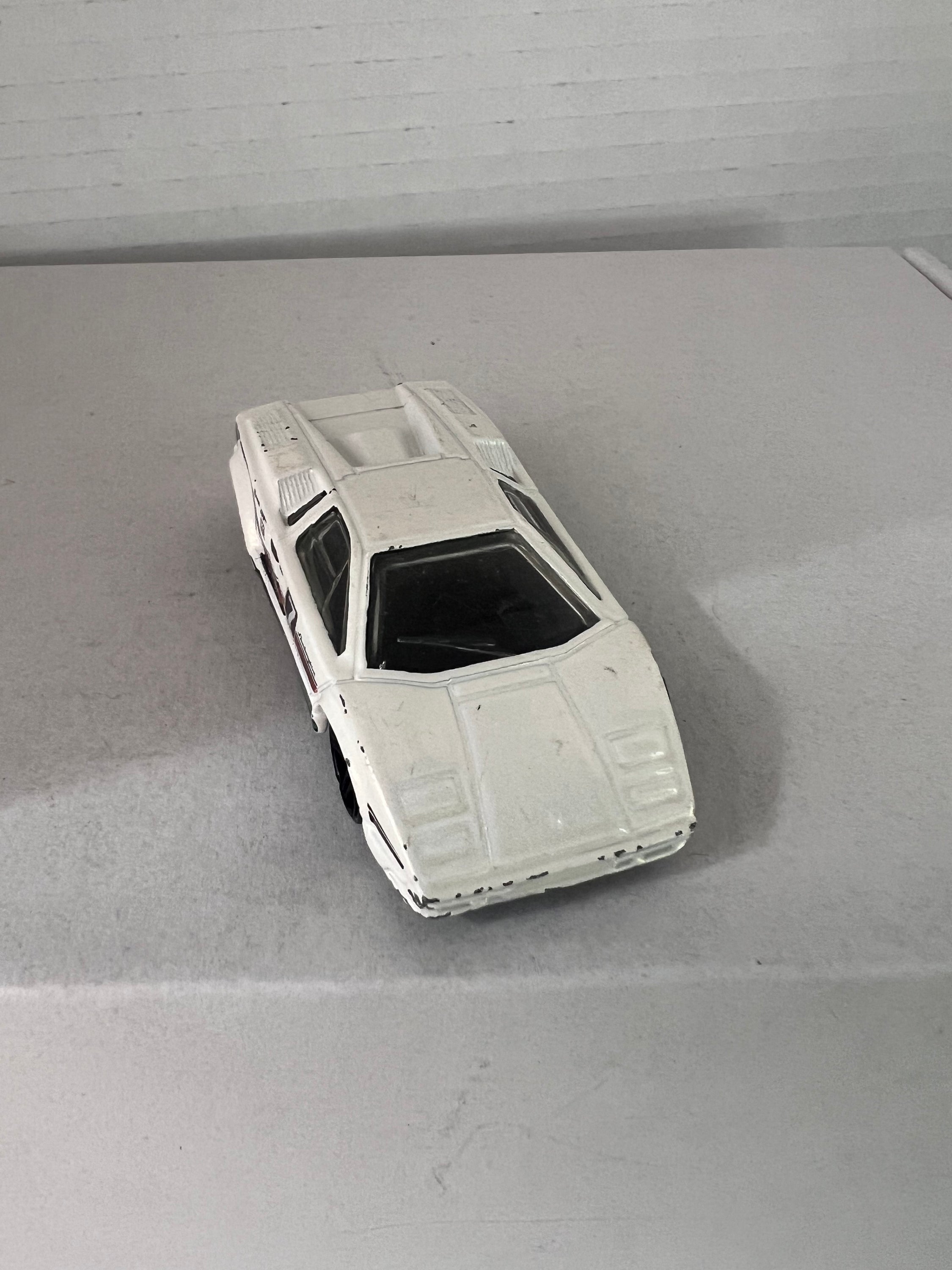 Hot Wheels 25th Anniversary Lamborghini Countach die-cast model in white, showcasing its sleek design and details.