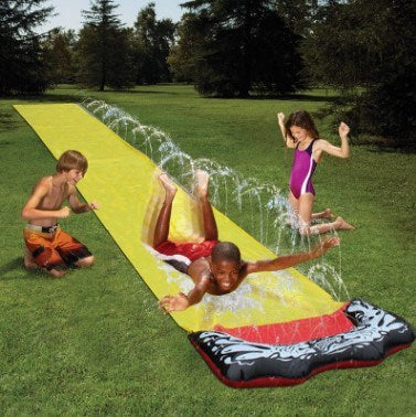 A colorful inflatable water slide set up in a garden, featuring a sprinkler system and children playing joyfully.