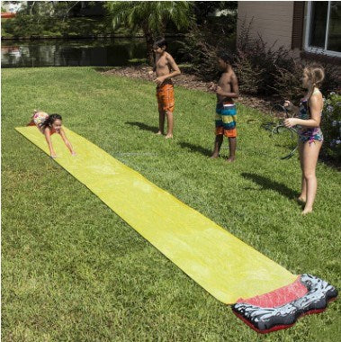 A colorful inflatable water slide set up in a garden, featuring a sprinkler system and children playing joyfully.