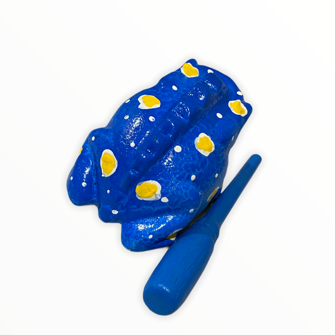 A beautifully crafted Medium Painted Winter Frog musical percussion instrument, showcasing vibrant colors and intricate details, with a small wooden mallet resting in its mouth.