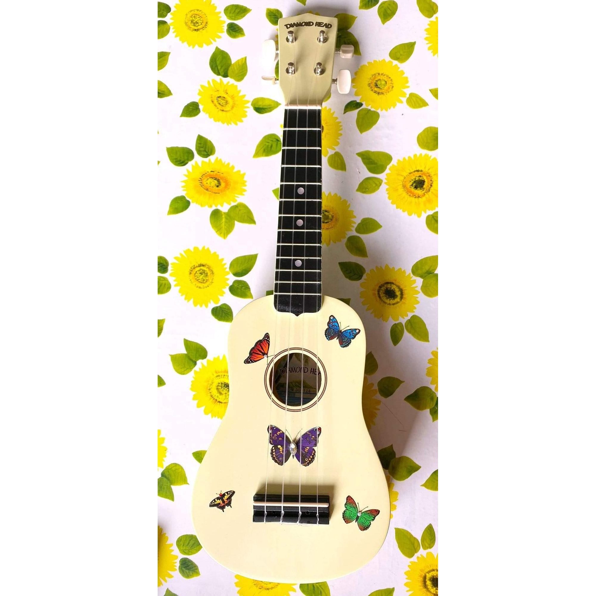 Rozanna's Butterfly Dream Ukulele featuring light yellow body with butterfly designs and faux crystal details.