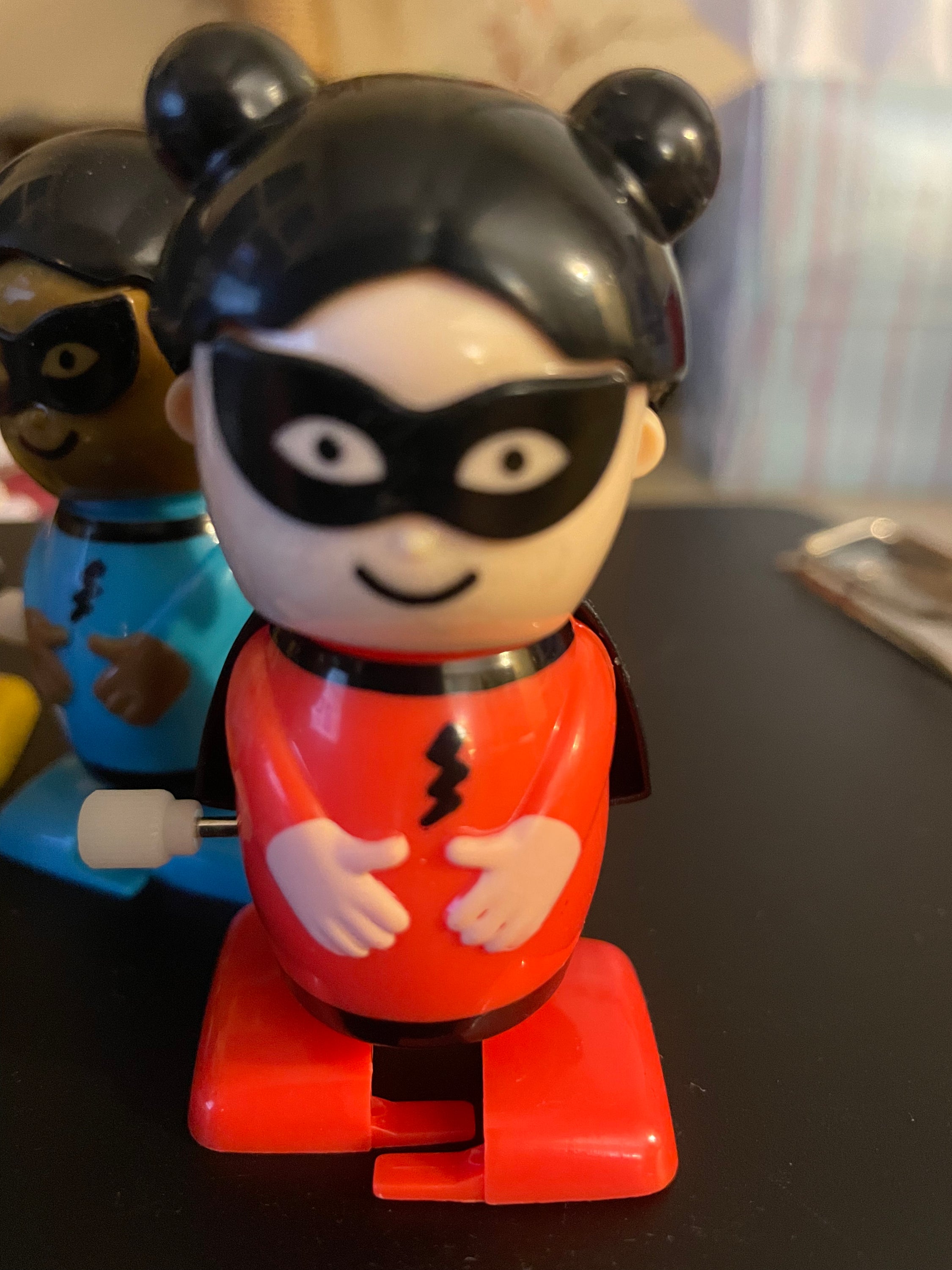 A colorful assortment of six wind-up superhero toys in yellow, red, and blue, showcasing their vibrant designs.