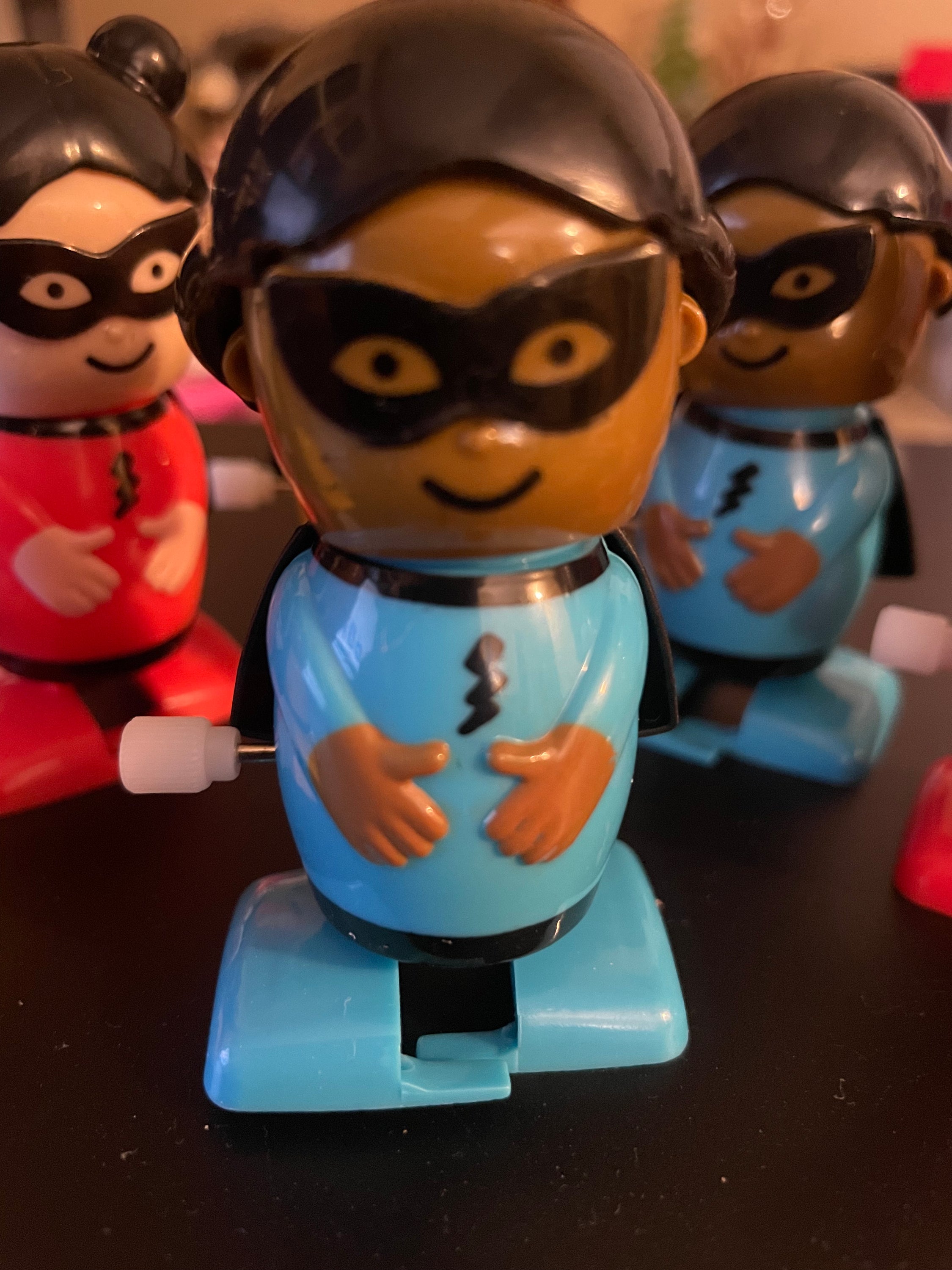 A colorful assortment of six wind-up superhero toys in yellow, red, and blue, showcasing their vibrant designs.