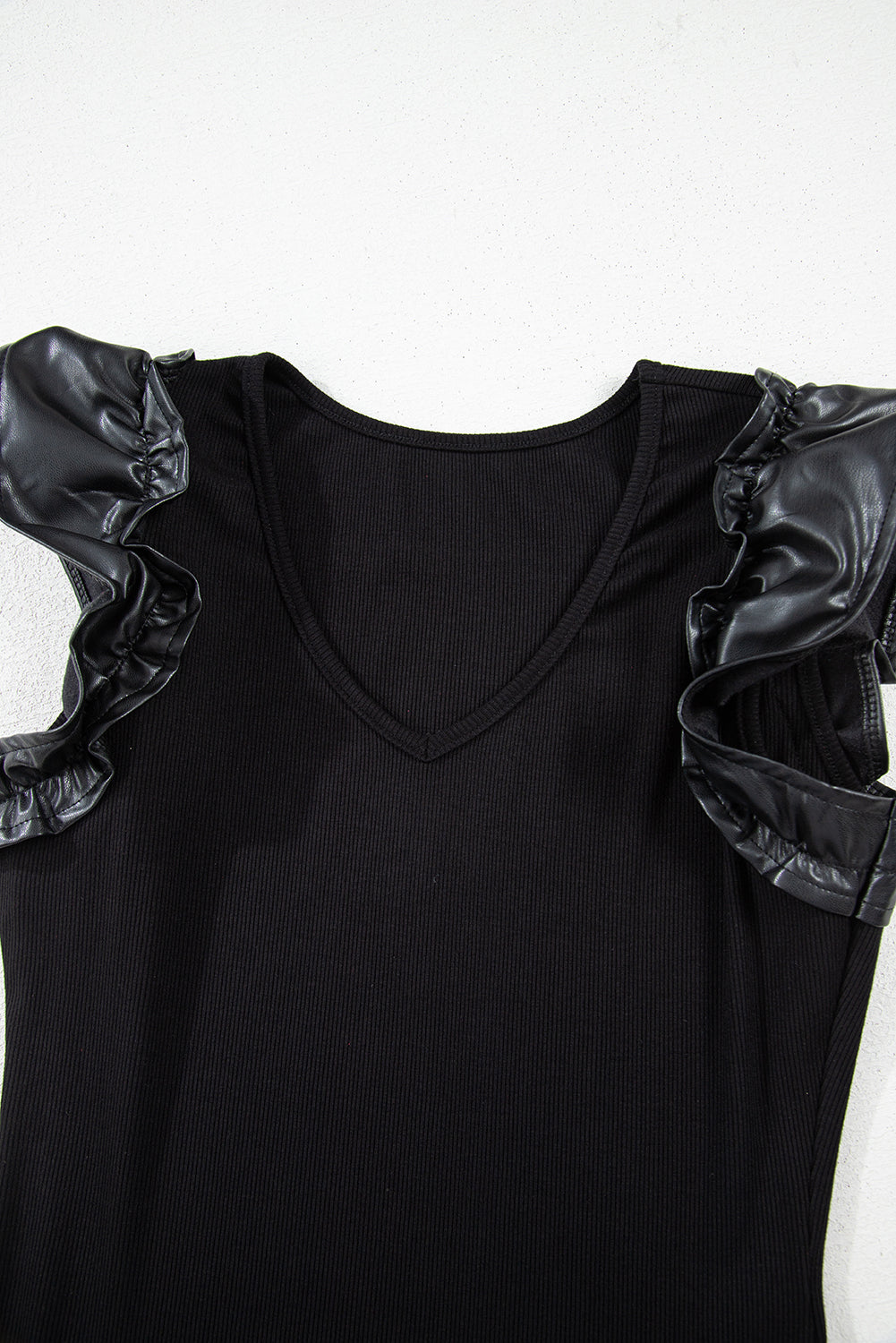 Solid ribbed leatherette bodysuit with ruffle sleeves and V-neckline, showcasing a modern and stylish design.
