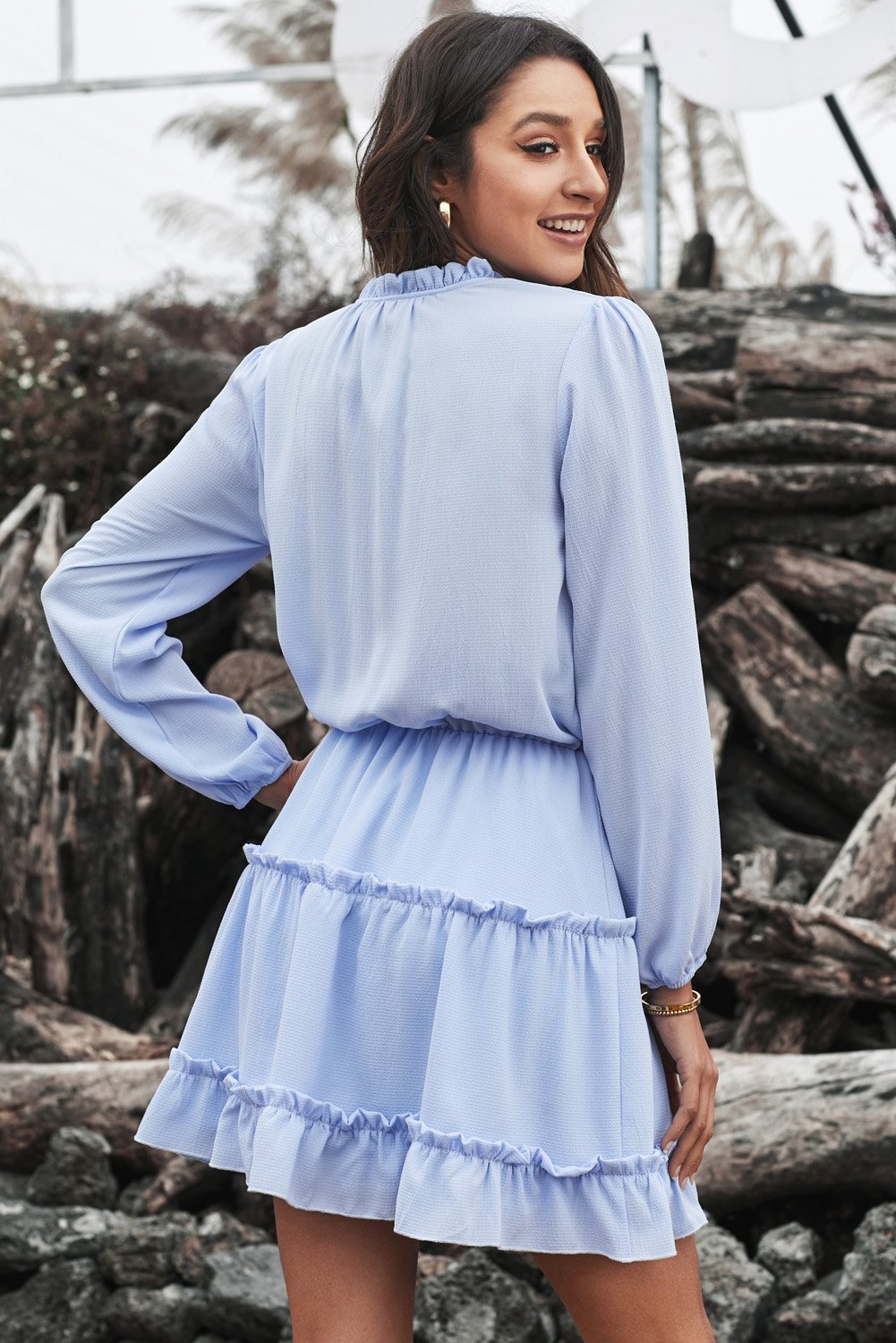 A stylish blue V neck long sleeve mini dress with ruffles and a tiered design, perfect for elegant occasions.