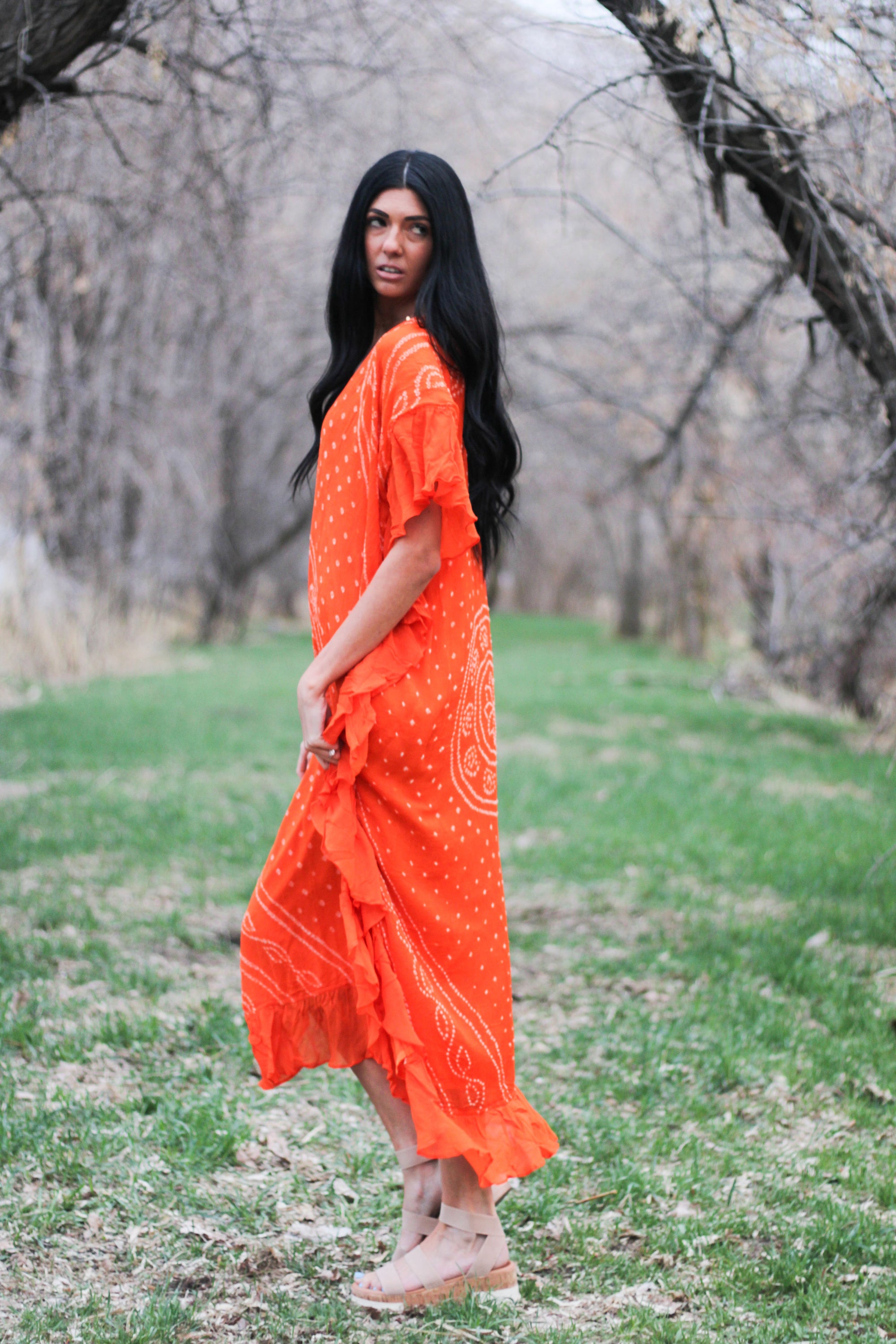 A vibrant tangerine Pinch Tie Dye Kaftan Maxi Dress with fringe details, showcasing its luxurious silk fabric and unique design.