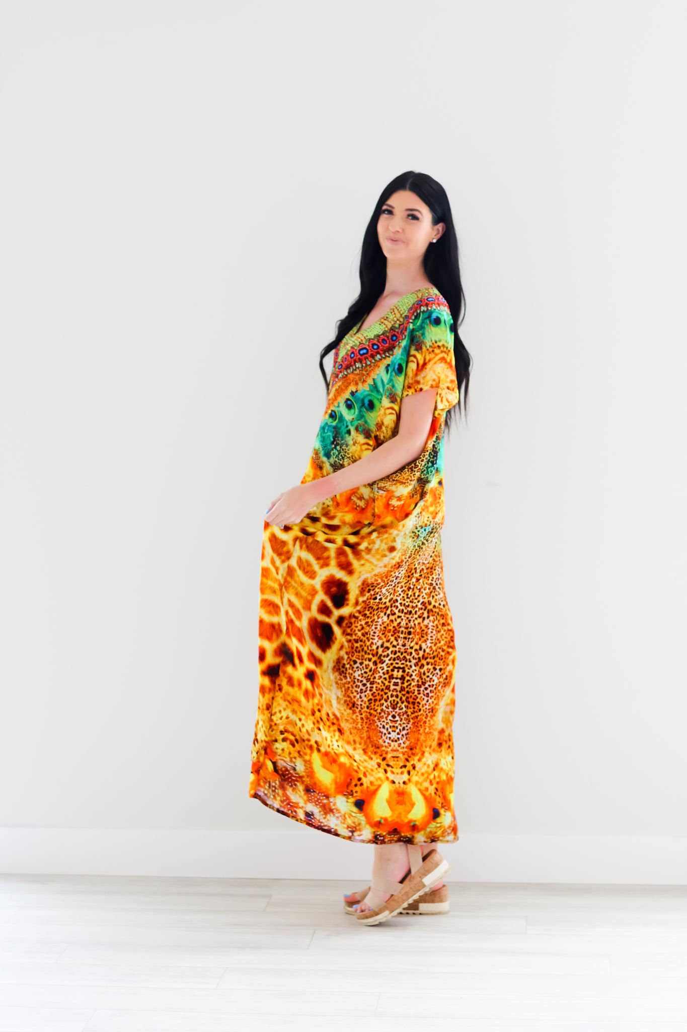 A vibrant yellow silk caftan dress featuring an animal print design, adorned with decorative stones and hand-applied beads, perfect for elegant occasions.