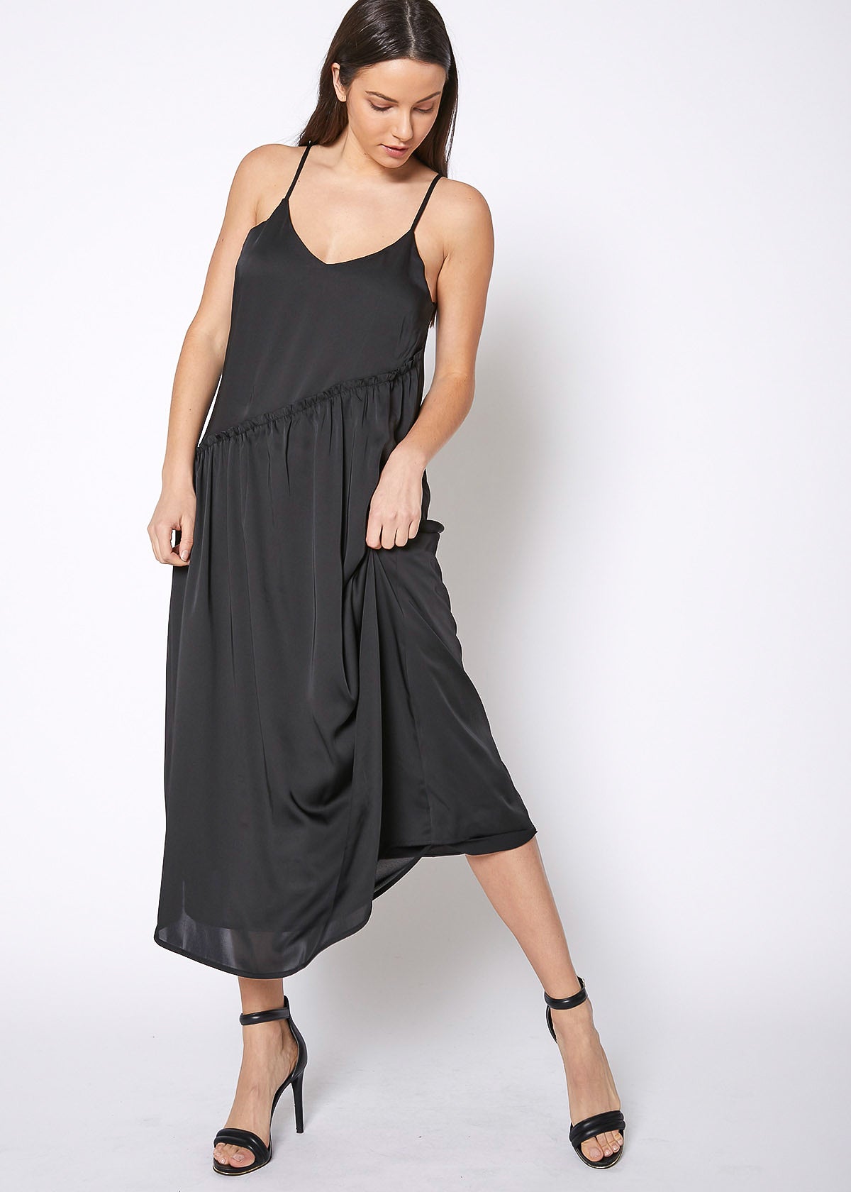 Women's black spaghetti strap maxi dress with diagonal ruffle patched detail, showcasing elegant design and silky satin fabric.