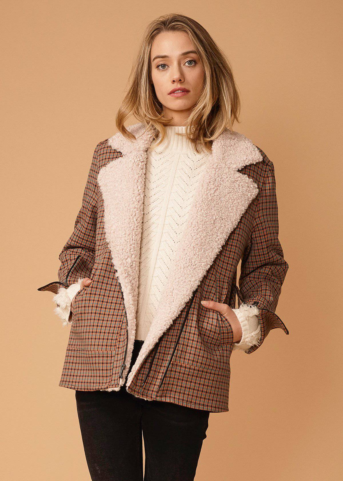 Asymmetrical zip front coat in peach gingham with shearling lapel and zipper cuffs, showcasing modern design and stylish details.