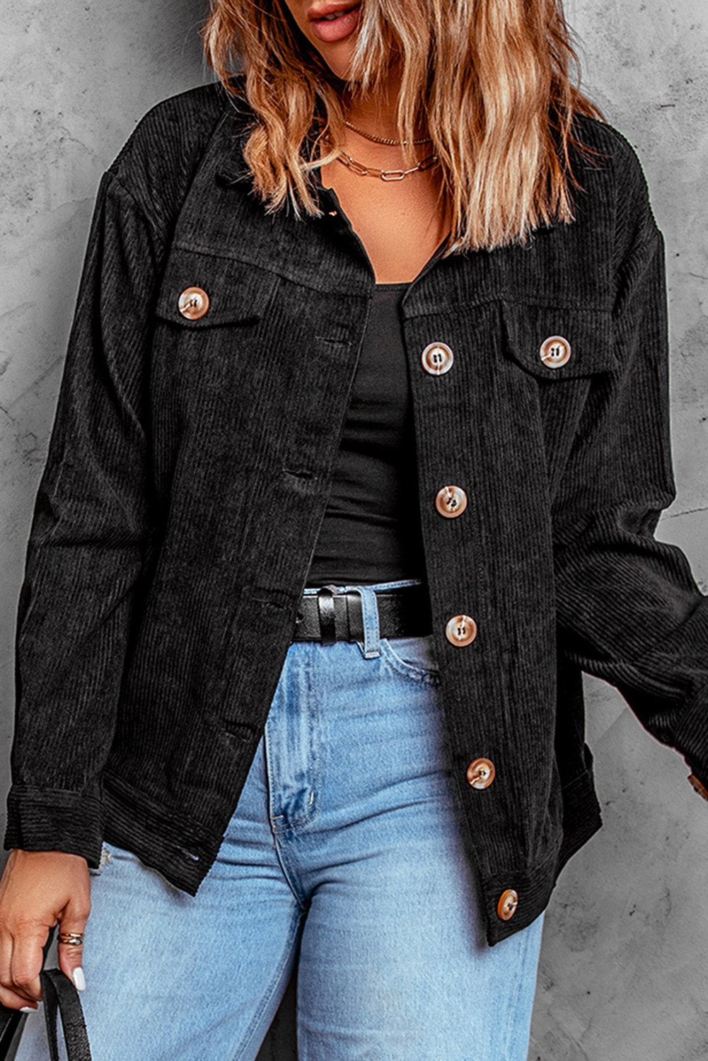 Black ribbed corduroy jacket with full sleeves and turn-down collar, featuring button closure and front pockets.