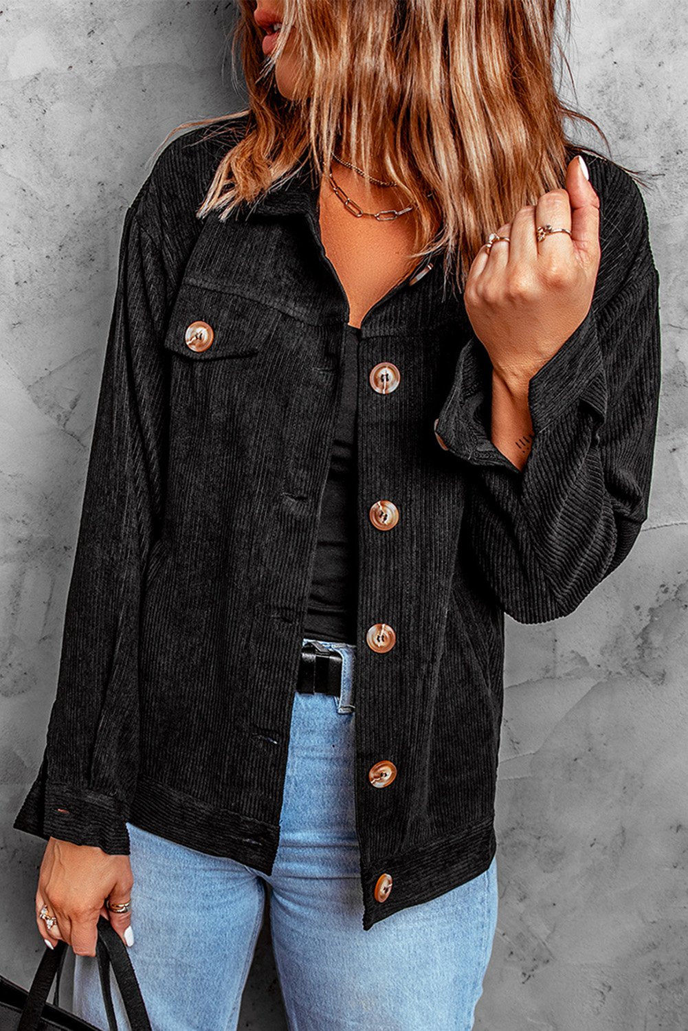 Black ribbed corduroy jacket with full sleeves and turn-down collar, featuring button closure and front pockets.