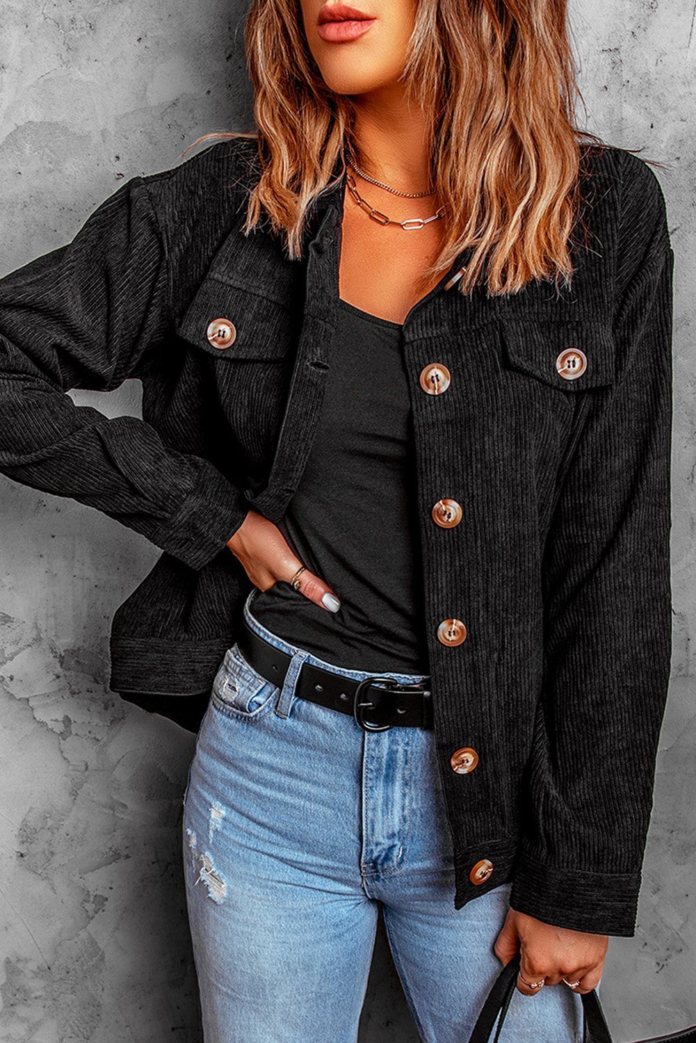 Black ribbed corduroy jacket with full sleeves and turn-down collar, featuring button closure and front pockets.