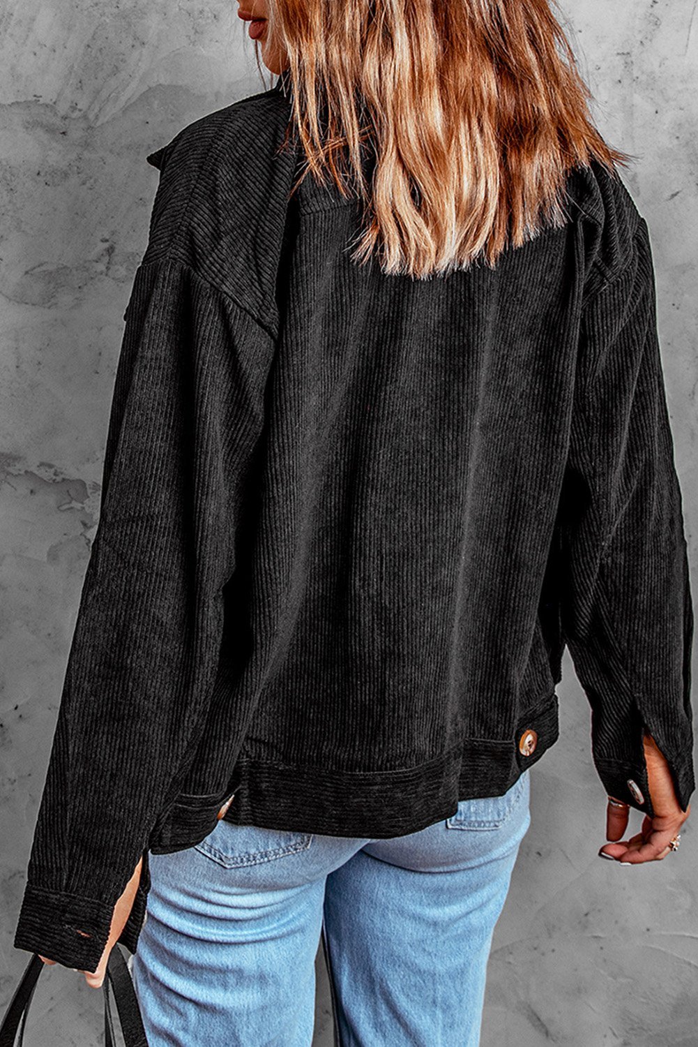 Black ribbed corduroy jacket with full sleeves and turn-down collar, featuring button closure and front pockets.