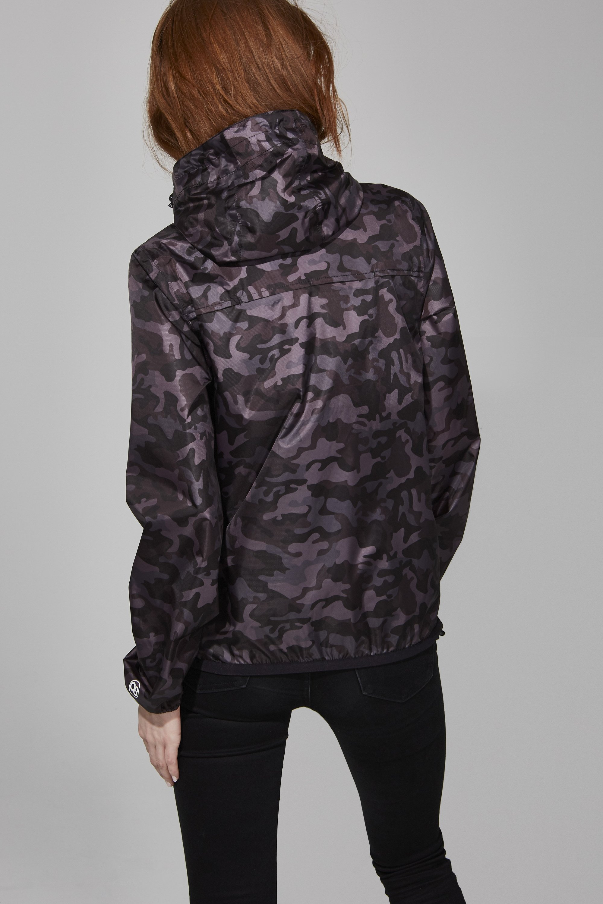 Women's black camo full zip packable rain jacket displayed on a mannequin, showcasing its stylish design and packable feature.