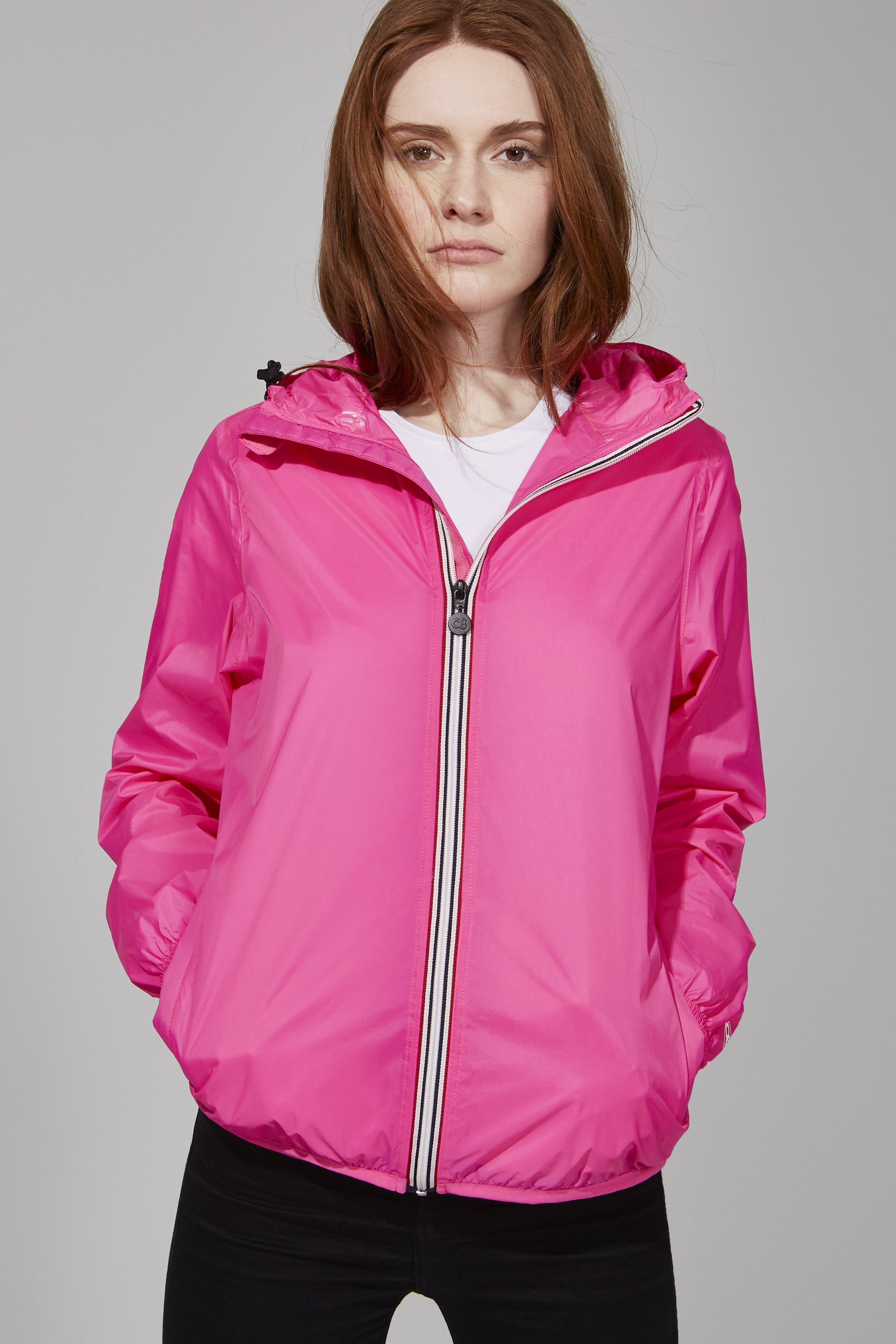 Women's pink fluo full zip packable rain jacket displayed on a mannequin, showcasing its vibrant color and stylish design.