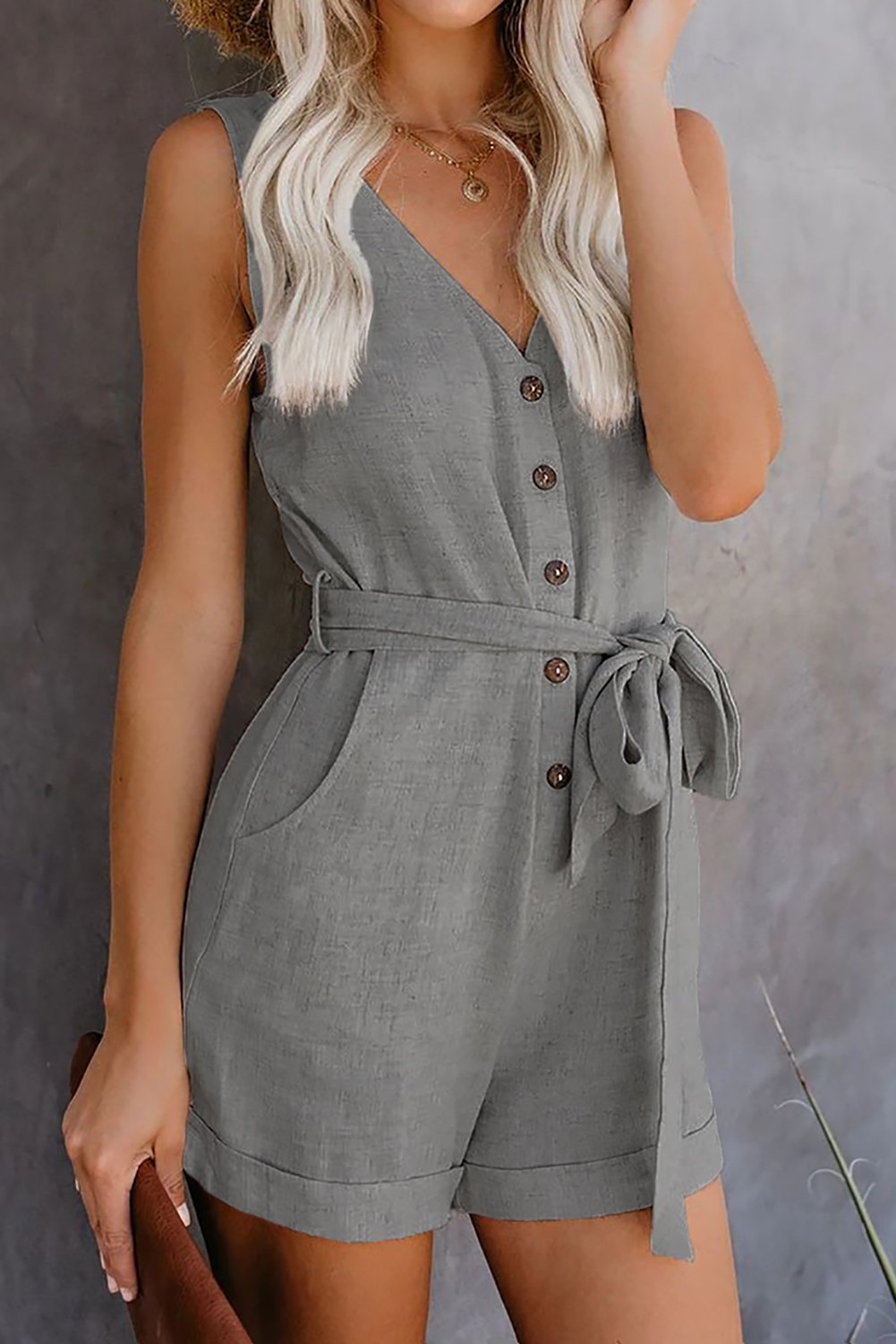 Casual gray sleeveless romper featuring a v-neck, button details, and a stylish waist belt, perfect for summer outings.