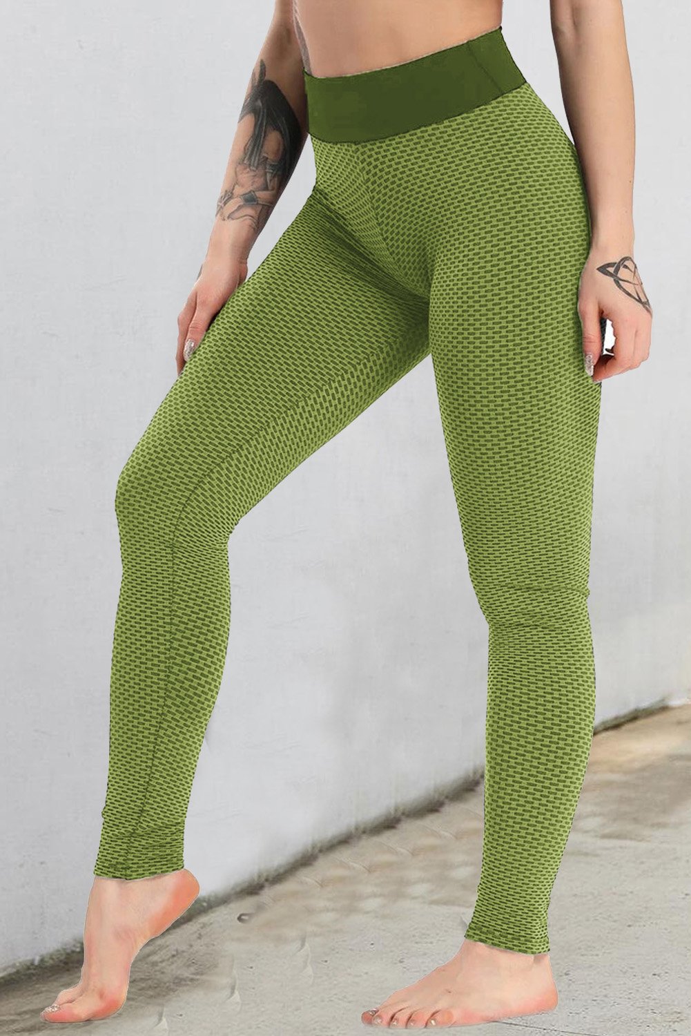 Women's army green high waisted butt lifting yoga gym leggings displayed on a flat surface, showcasing their stretchy fabric and flattering design.