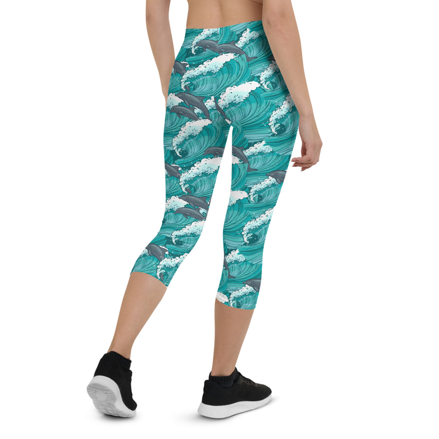 A pair of Women's Dolphin and Waves Capri Leggings featuring vibrant dolphin and wave graphics, designed for comfort and performance.