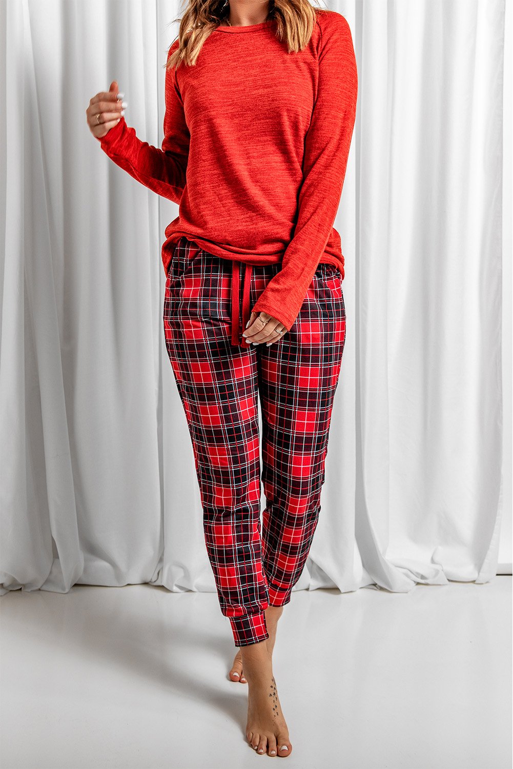 A cozy red top paired with trendy plaid pants, perfect for winter loungewear, featuring full sleeves and pockets for added comfort.
