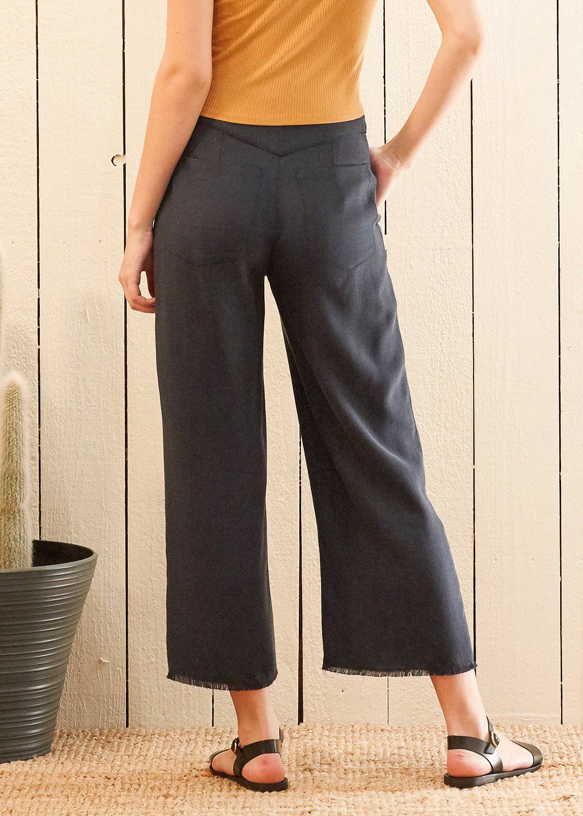 Women's navy cropped pants featuring a fringe raw hem and high-waisted design, made from soft Tencel fabric.