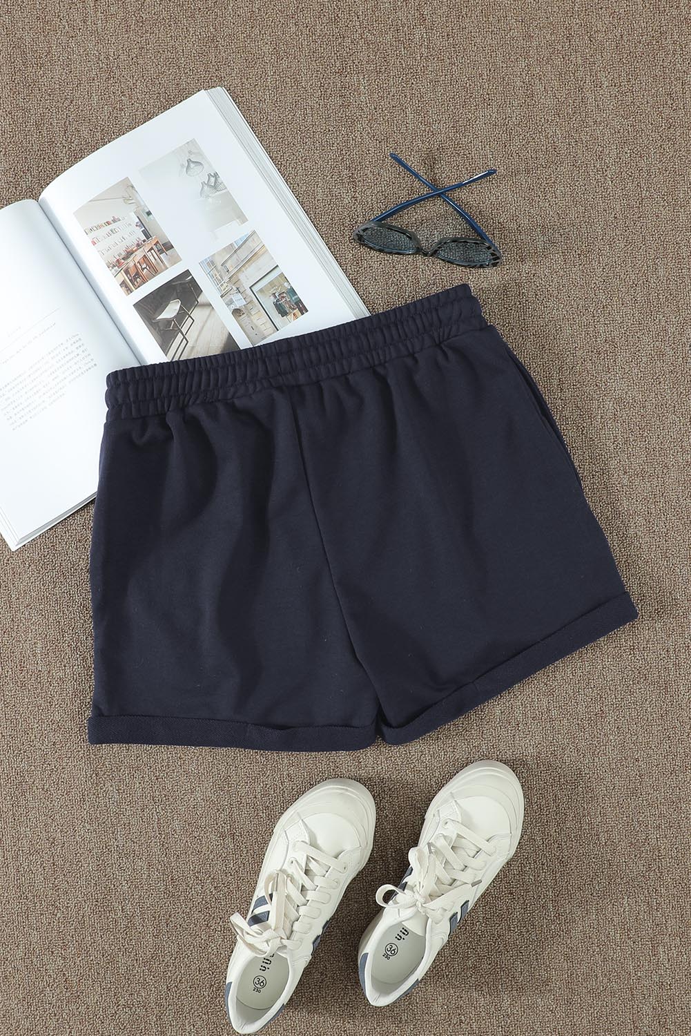 A pair of navy blue women's lounge shorts featuring a tie waist, cuffed hem, and side pockets, perfect for summer wear.