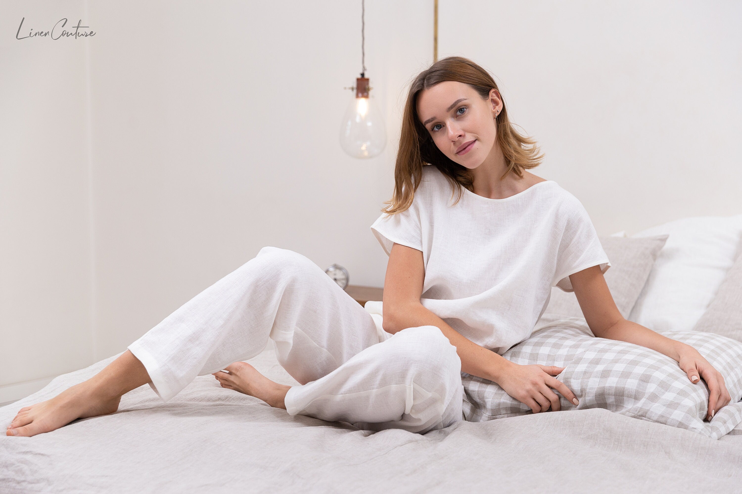 Elegant white linen pajama set featuring a boat neckline, short sleeves, and long pants with an adjustable waistband, perfect for lounging.