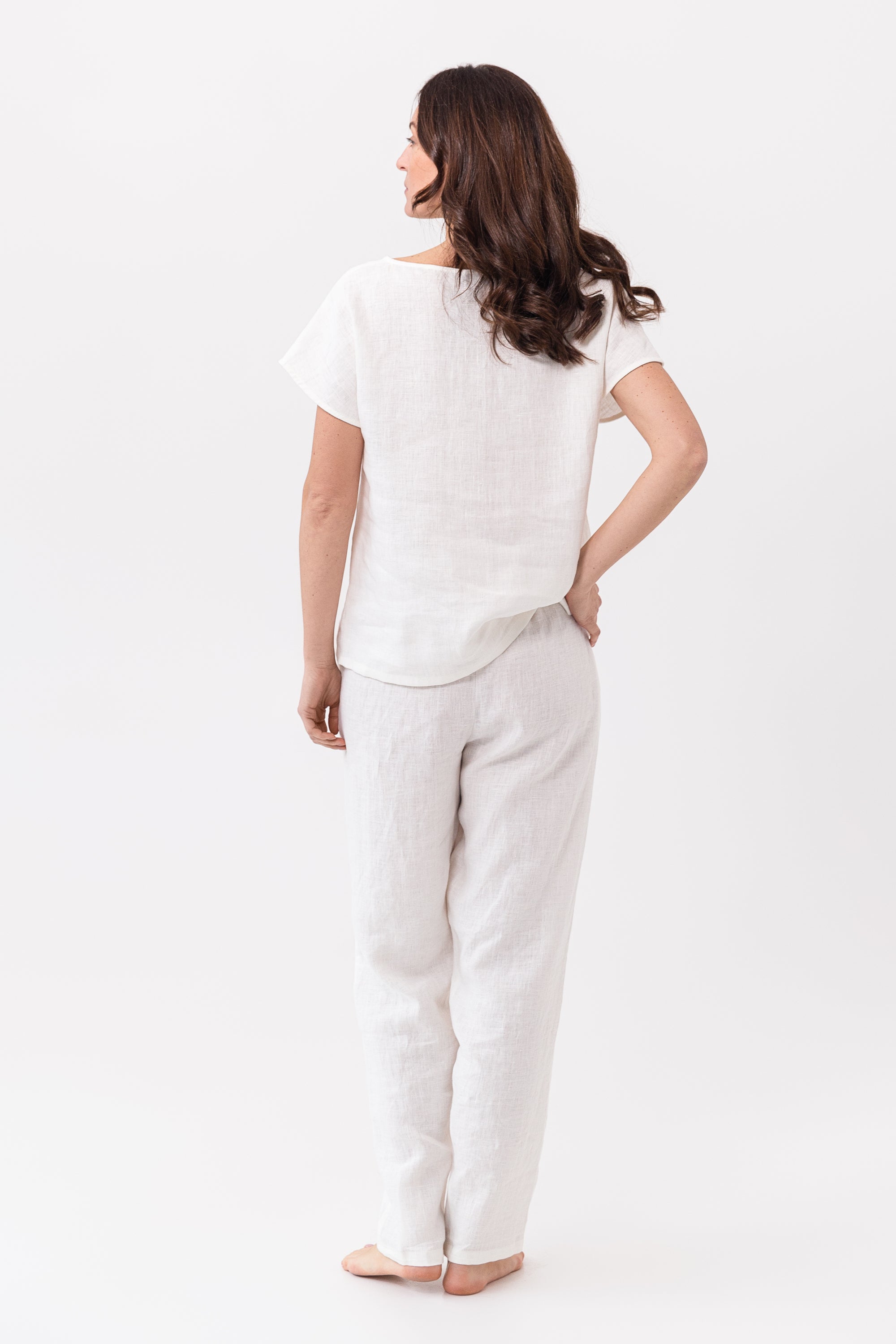 Elegant white linen pajama set featuring a boat neckline, short sleeves, and long pants with an adjustable waistband, perfect for lounging.
