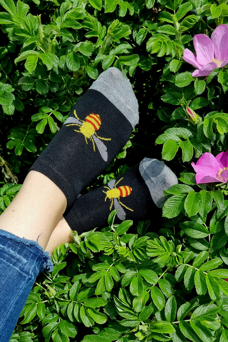 A pair of low-cut socks featuring a vibrant yellow bee design on a black background, showcasing their stylish and playful look.