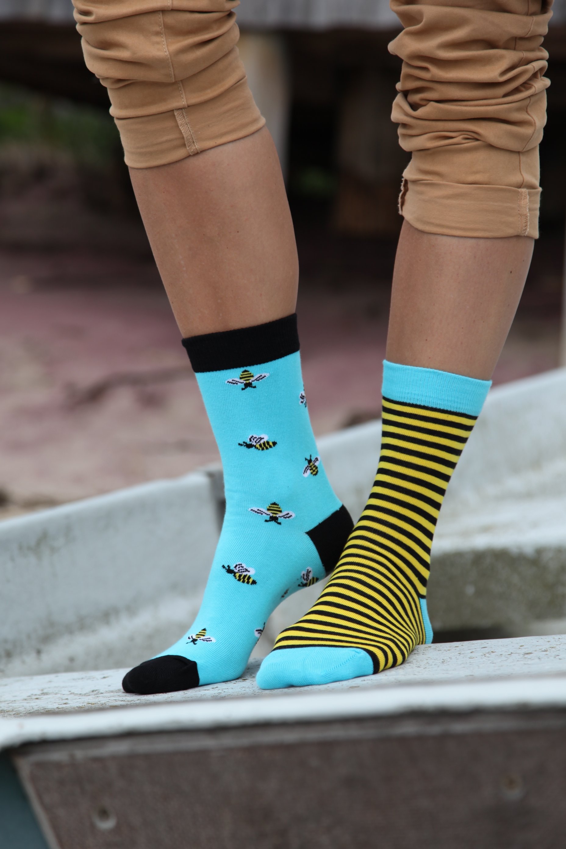 A pair of women's cotton socks featuring one striped sock and one with bees, in vibrant blue and yellow colors.