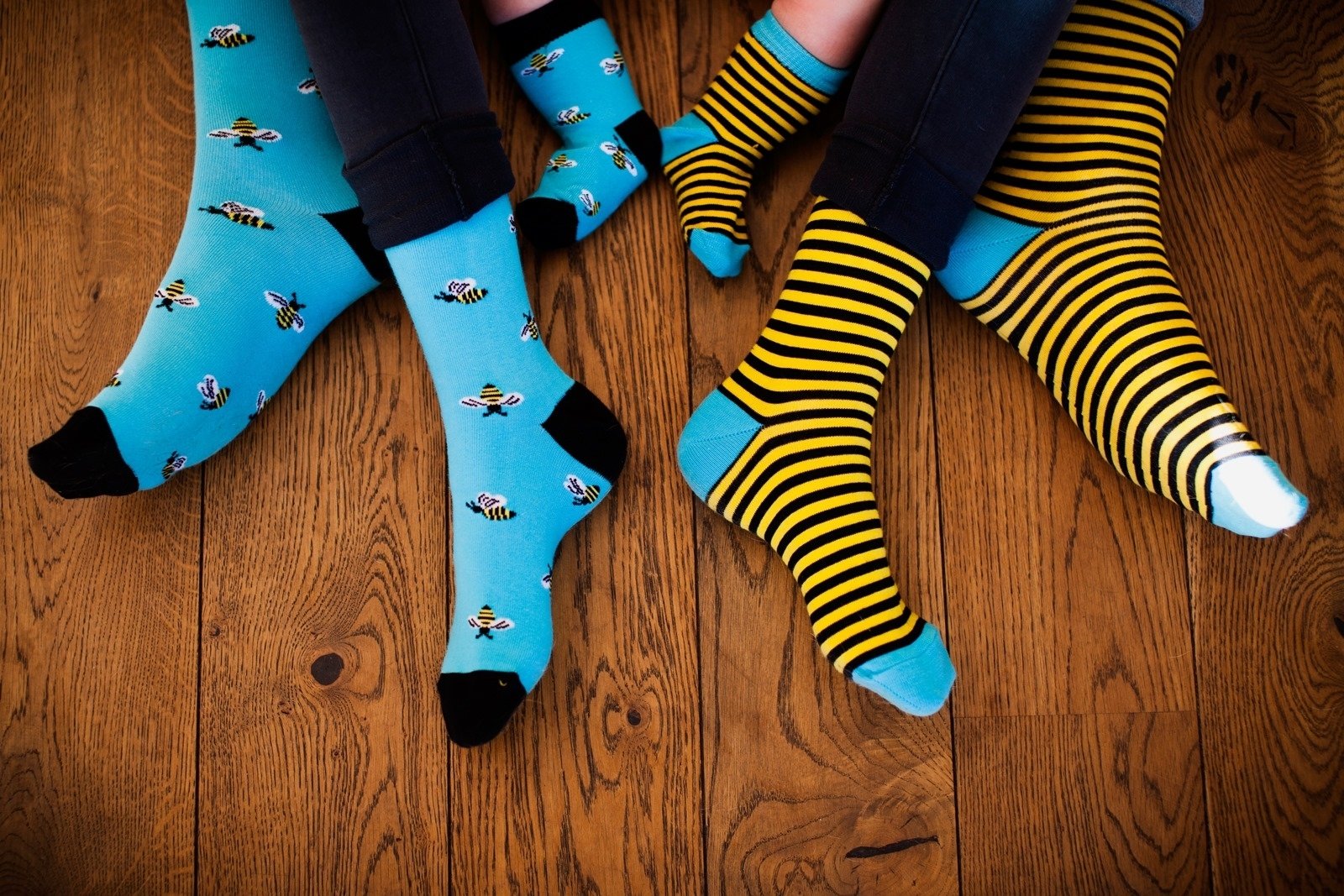 A pair of women's cotton socks featuring one striped sock and one with bees, in vibrant blue and yellow colors.