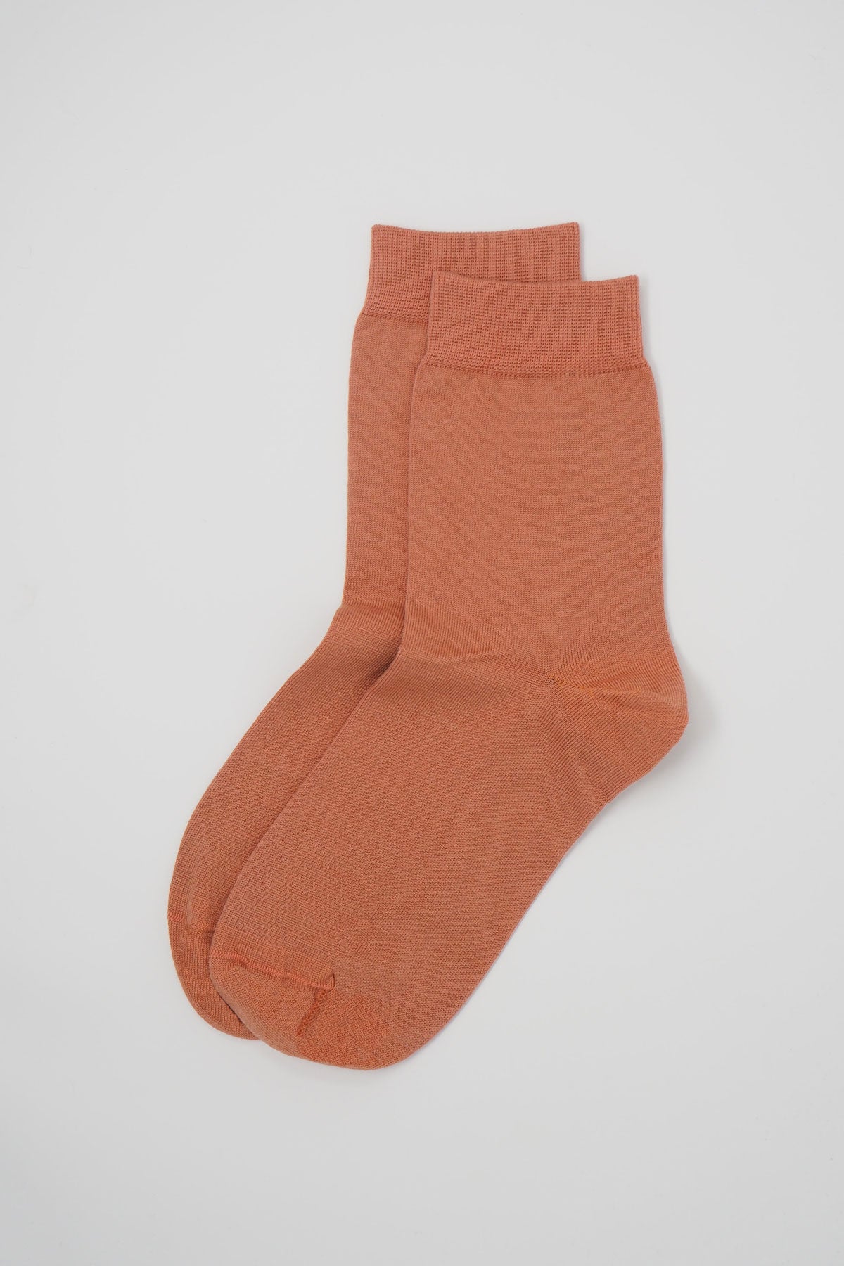 A pair of classic women's socks in peach color, made from luxurious Mercerised Egyptian cotton, showcasing a seamless toe design.