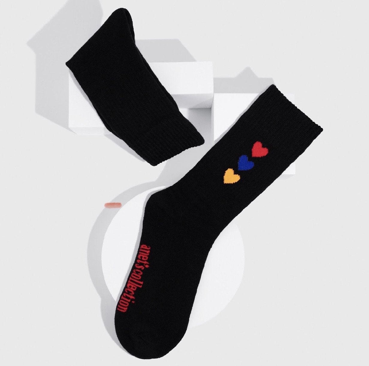 Hearts of Armenia Socks featuring jacquard design with red, orange, and blue hearts on a black and white background.