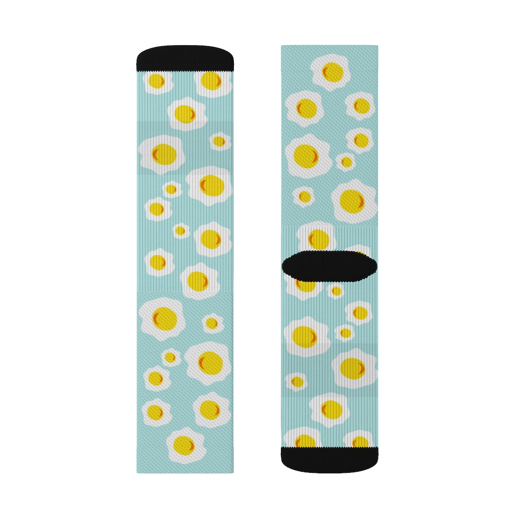 A pair of colorful novelty socks featuring a sunny side up eggs print, showcasing their vibrant design and comfortable ribbed tube.