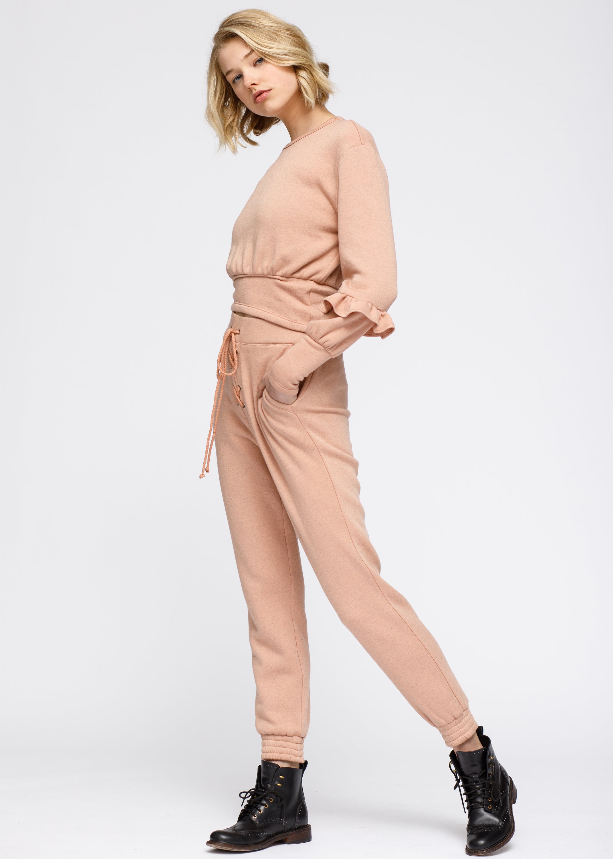 Peach crewneck sweatshirt with ruffle sleeve and elasticized waist, showcasing a stylish and comfortable design.