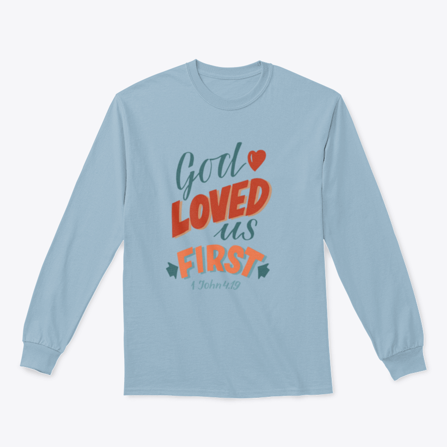 A modern t-shirt featuring the motivational quote 'God Loved Us First', made from soft cotton fabric, displayed on a neutral background.