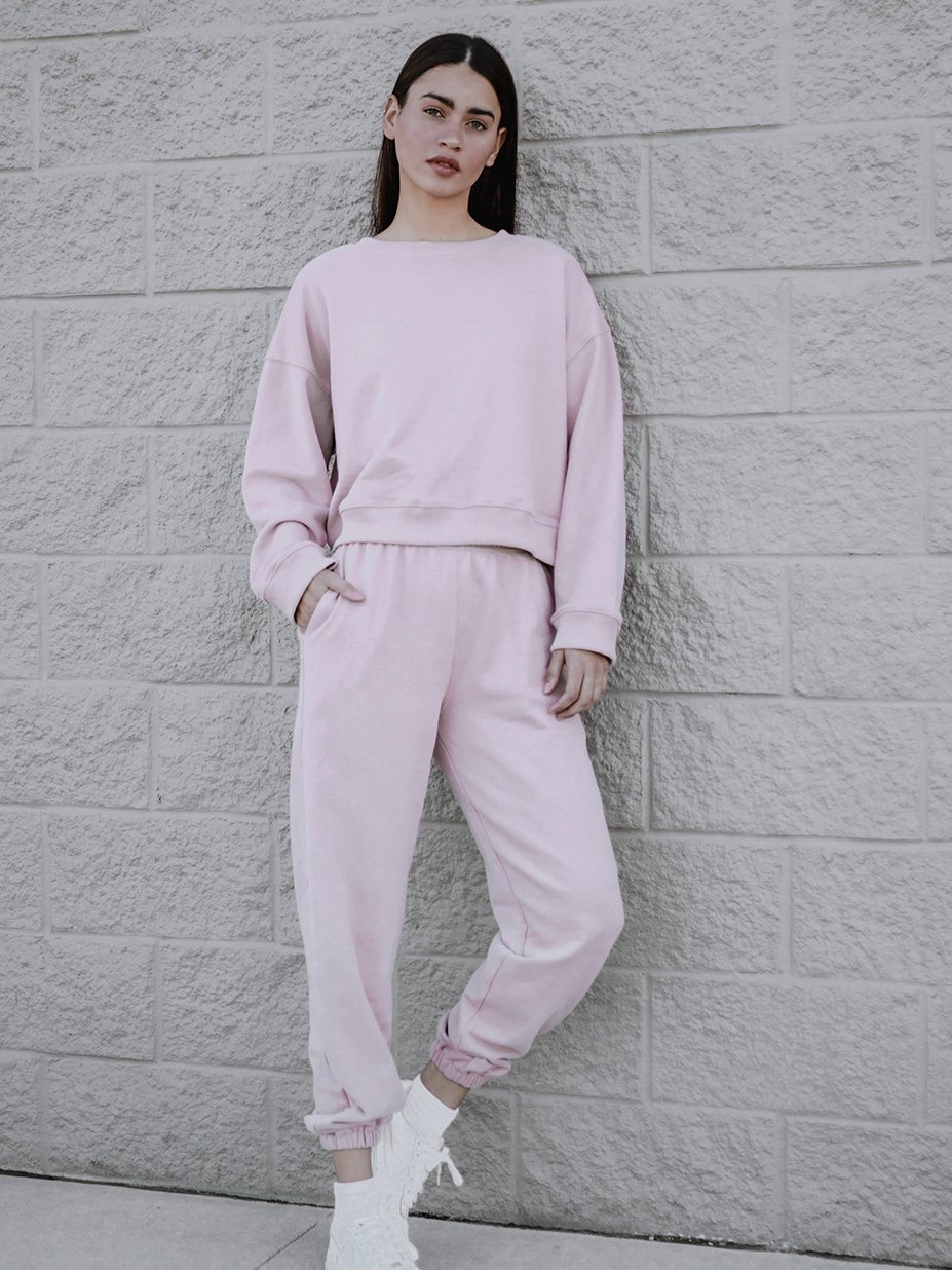 A soft pink sweatshirt with a rounded neckline and ribbed trim, showcasing a trendy boxy silhouette.