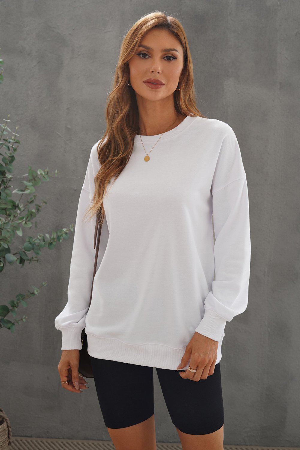 A cozy white oversized sweatshirt with a drop shoulder design, perfect for casual wear in fall and winter.