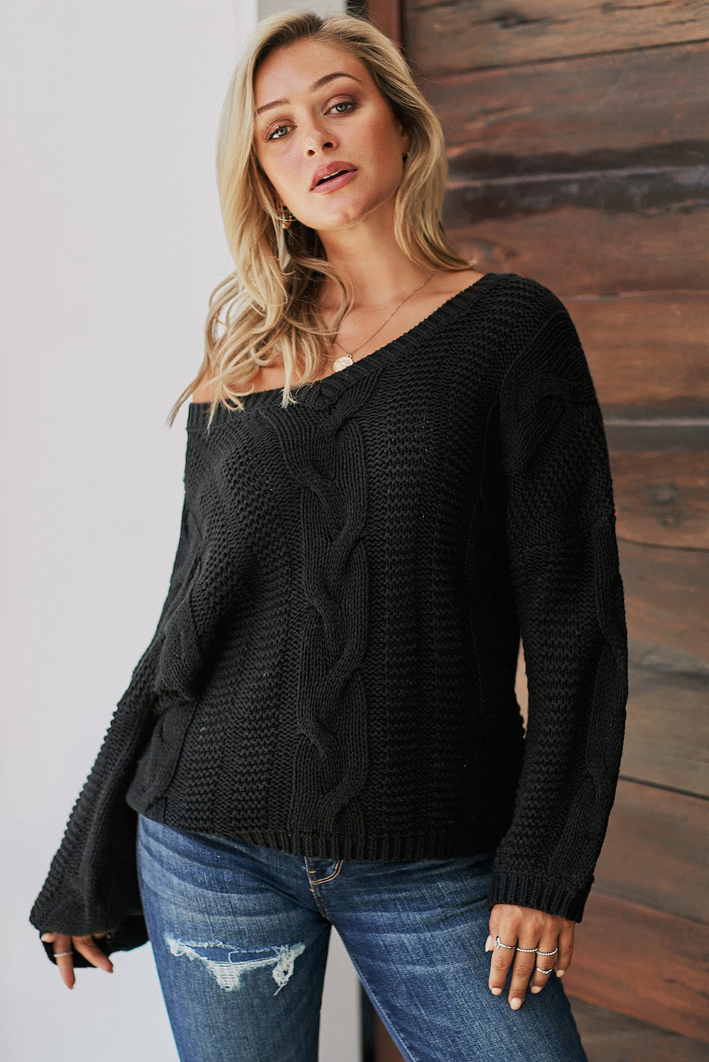 A stylish black braided knit sweater with a v-neckline and puffy sleeves, perfect for winter wear.