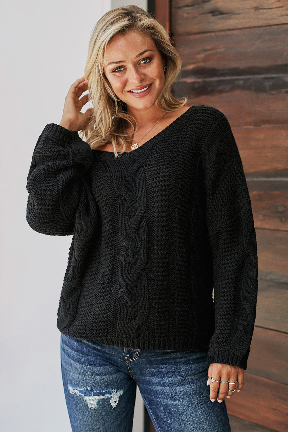 A stylish black braided knit sweater with a v-neckline and puffy sleeves, perfect for winter wear.