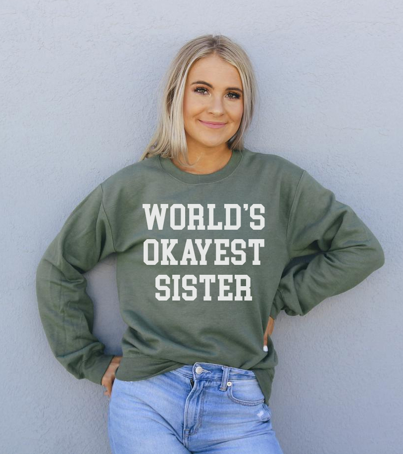 A cozy unisex sweatshirt featuring the phrase 'World's Okayest Sister' in a fun font, perfect for casual wear.