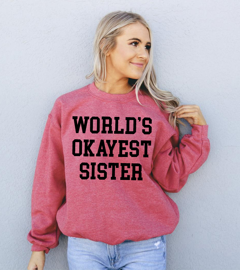 A cozy unisex sweatshirt featuring the phrase 'World's Okayest Sister' in a fun font, perfect for casual wear.