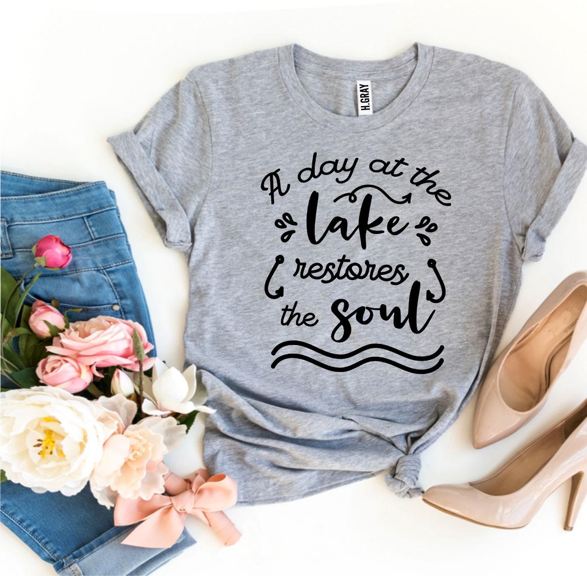 A Day At The Lake Restores The Soul T-shirt in soft ring spun cotton with a vibrant print, showcasing a serene lake scene.