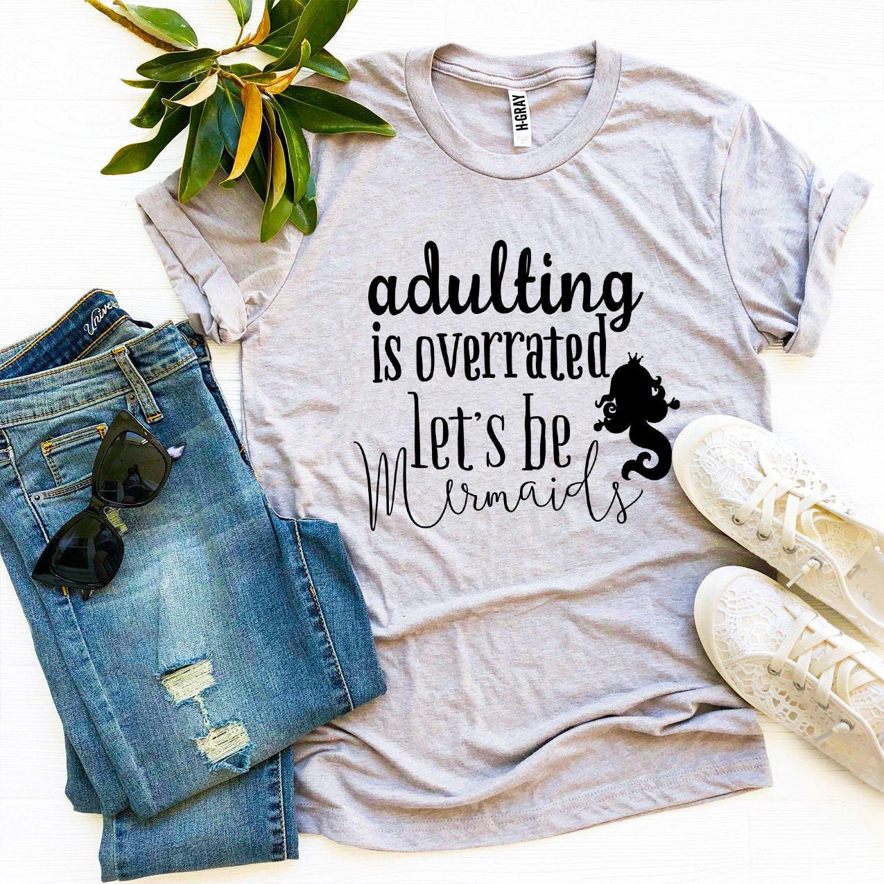 A soft, premium quality T-shirt featuring the phrase 'Adulting Is Overrated Let’s Be Mermaids' in a playful design.