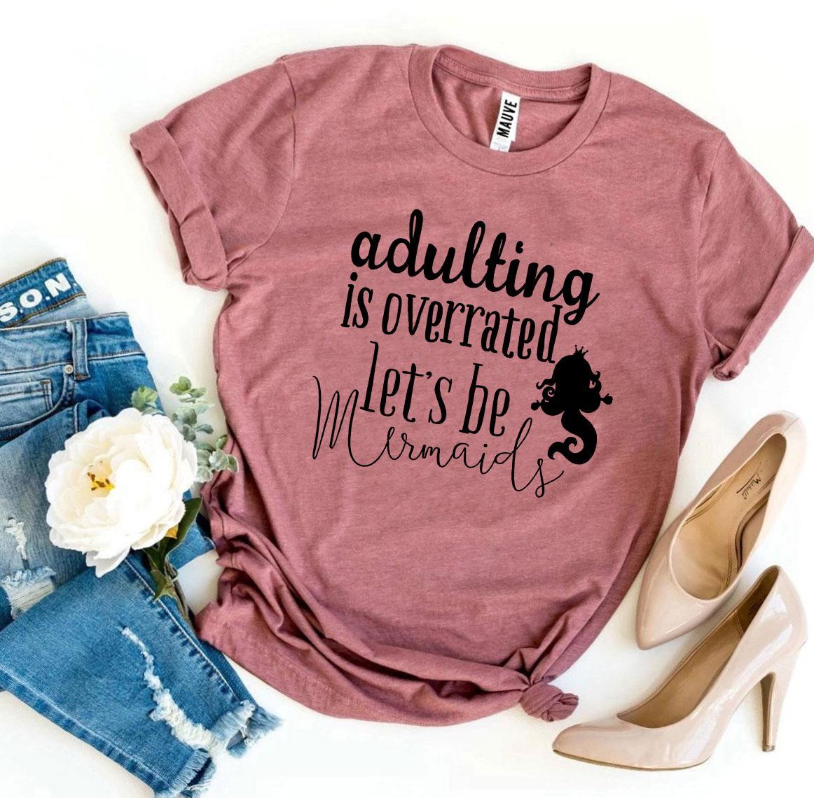 A soft, premium quality T-shirt featuring the phrase 'Adulting Is Overrated Let’s Be Mermaids' in a playful design.